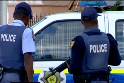 Two South African policemen standing by police vehicle.