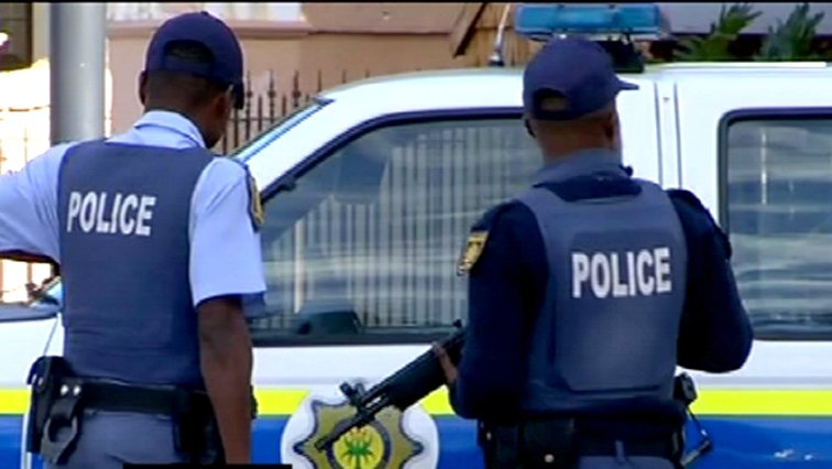Two South African policemen standing by police vehicle.