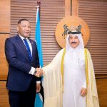 Two men handshake in formal attire.