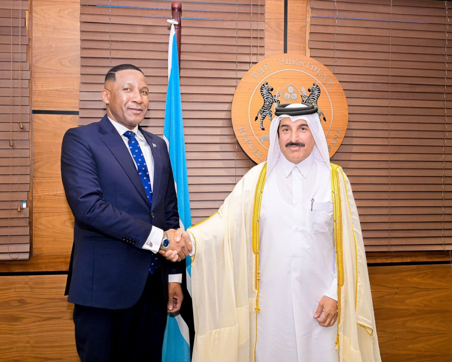 Two men handshake in formal attire.