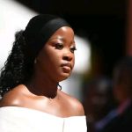 Woman in black headband, white off-shoulder top.