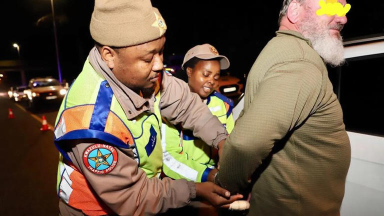 Traffic officers arresting man at night checkpoint