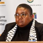 Person at South Africa event with banners behind.