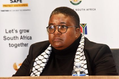 Person at South Africa event with banners behind.