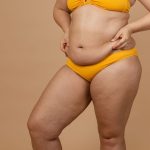 Person in yellow bikini on beige background.