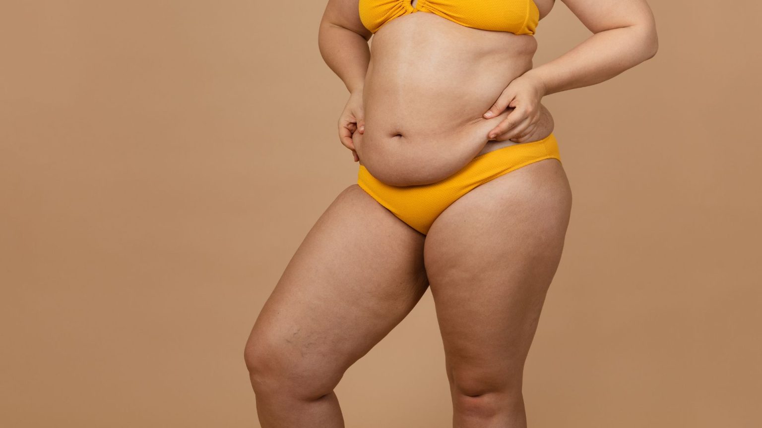 Person in yellow bikini on beige background.