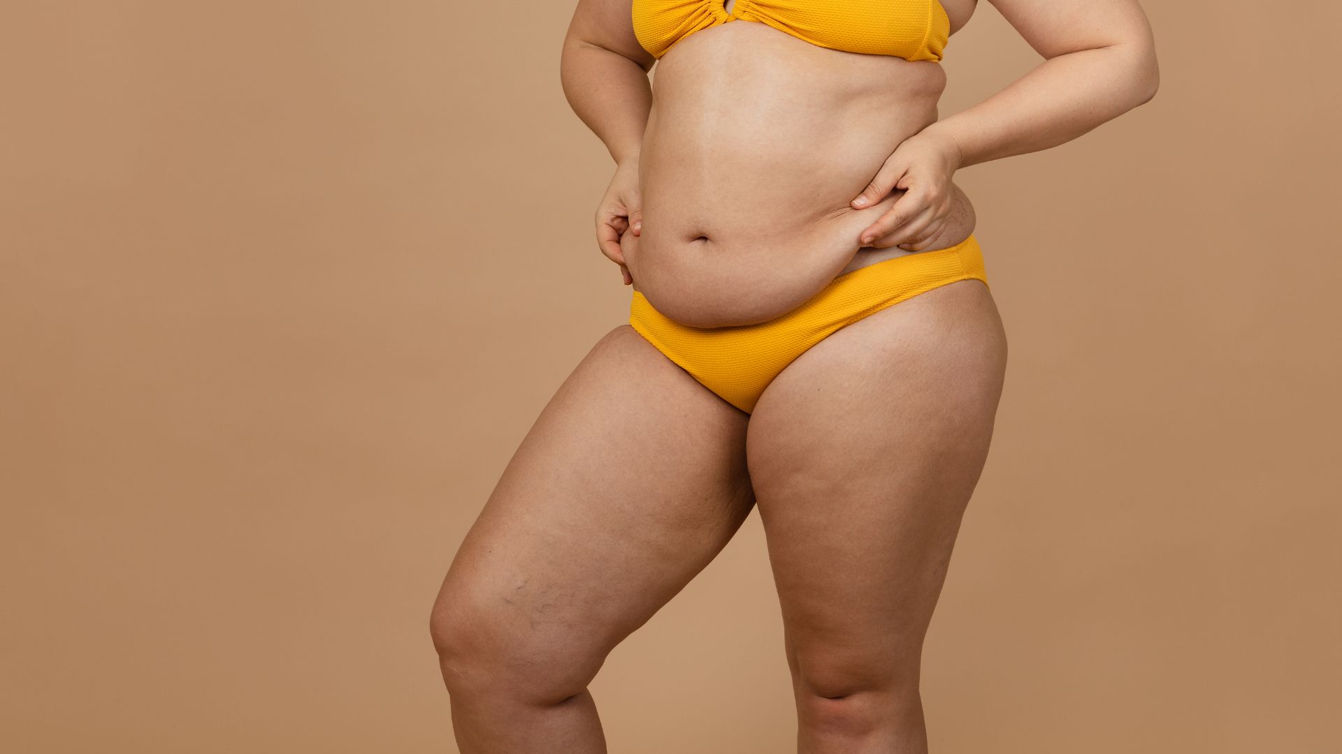 Person in yellow bikini on beige background.