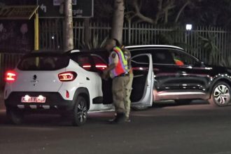Traffic officer inspecting cars at night in South Africa.