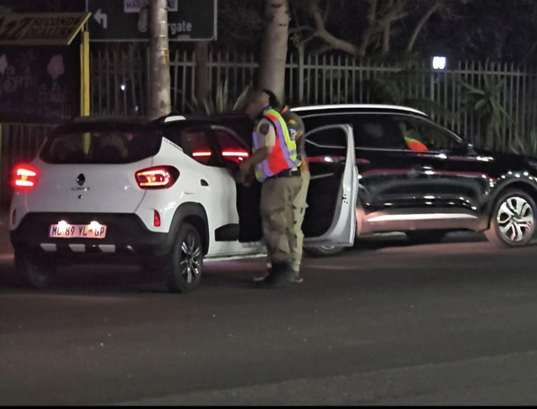 Traffic officer inspecting cars at night in South Africa.