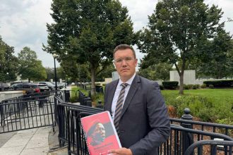 Man holding red cover document outdoors.