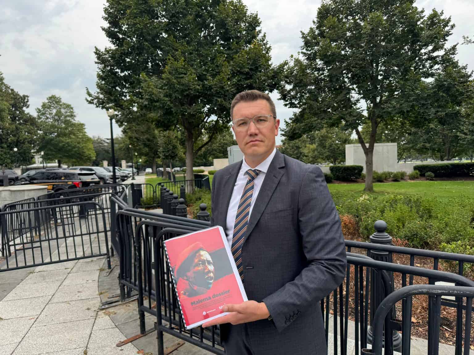 Man holding red cover document outdoors.