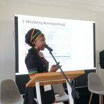 Woman presenting at Madibeng Municipal event.