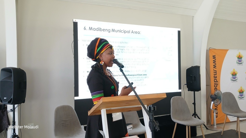 Woman presenting at Madibeng Municipal event.