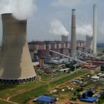 Power station cooling towers emitting steam in landscape.