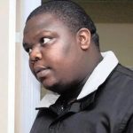 Man in black jacket looking sideways indoors.