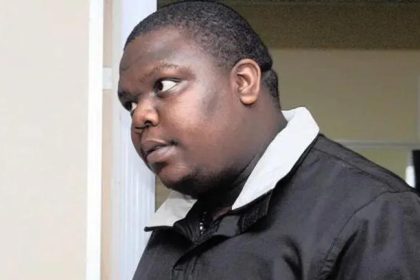 Man in black jacket looking sideways indoors.