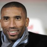 Smiling man wearing a scarf and jacket.