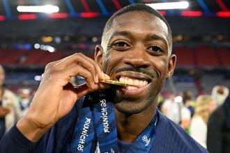 Footballer celebrates with gold medal on field.