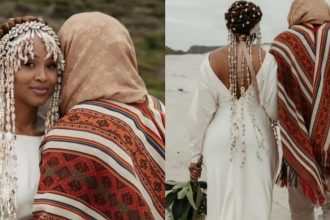 Couple in traditional attire on a beach.