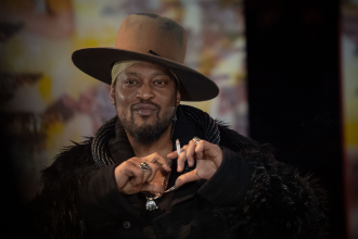 Person with hat making heart gesture.