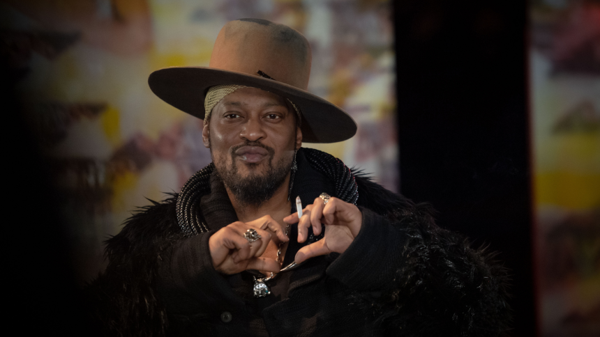 Person with hat making heart gesture.