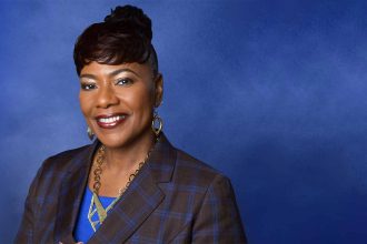 Smiling woman in blue background, professional attire.