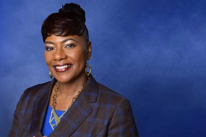 Smiling woman in blue background, professional attire.