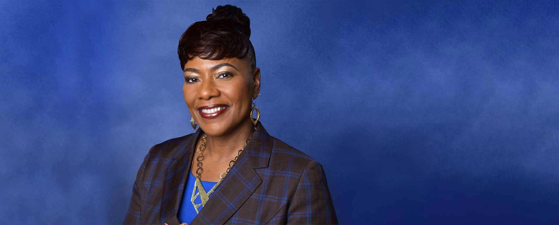 Smiling woman in blue background, professional attire.