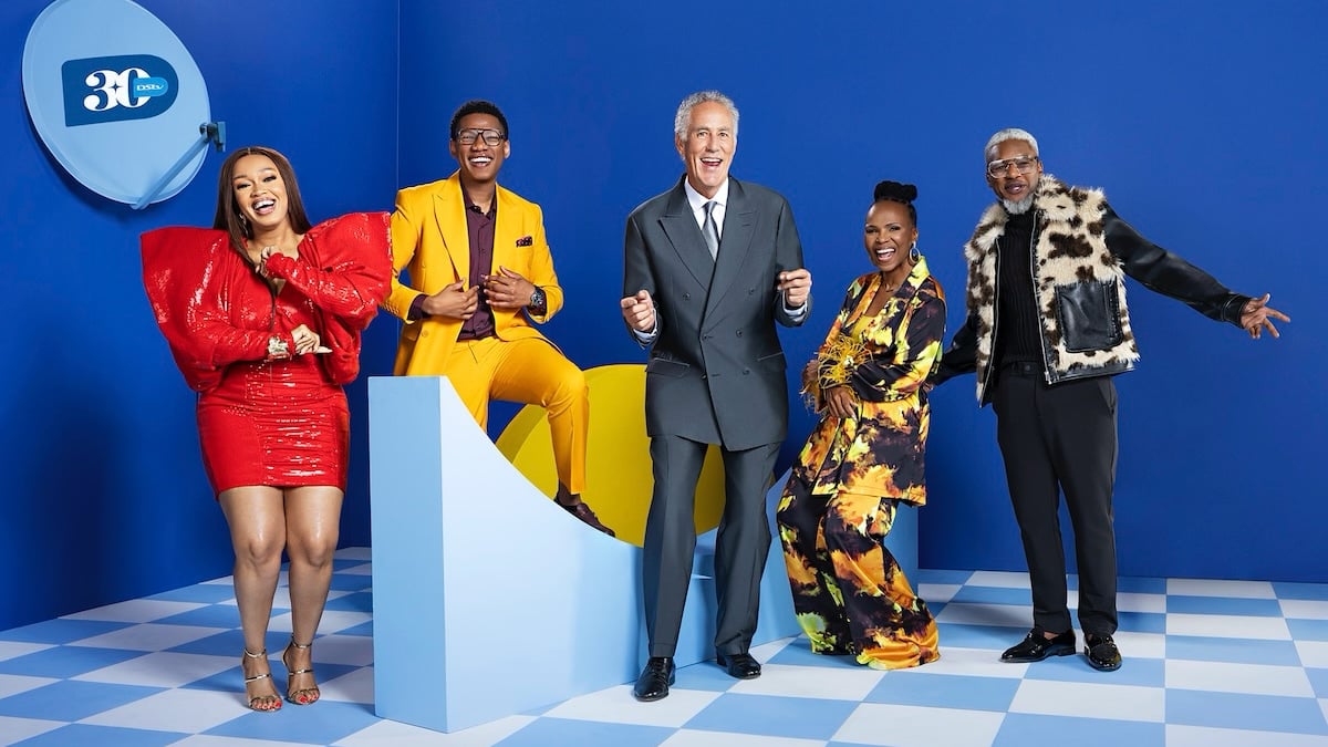 Group of five people smiling on blue background.