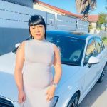 Woman posing with white Audi car in suburb.