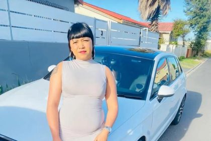 Woman posing with white Audi car in suburb.