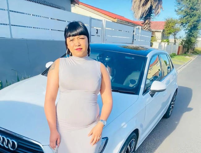 Woman posing with white Audi car in suburb.