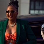 Fashionable woman smiling beside luxury car.