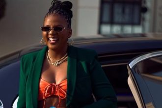 Fashionable woman smiling beside luxury car.
