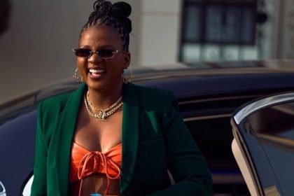 Fashionable woman smiling beside luxury car.
