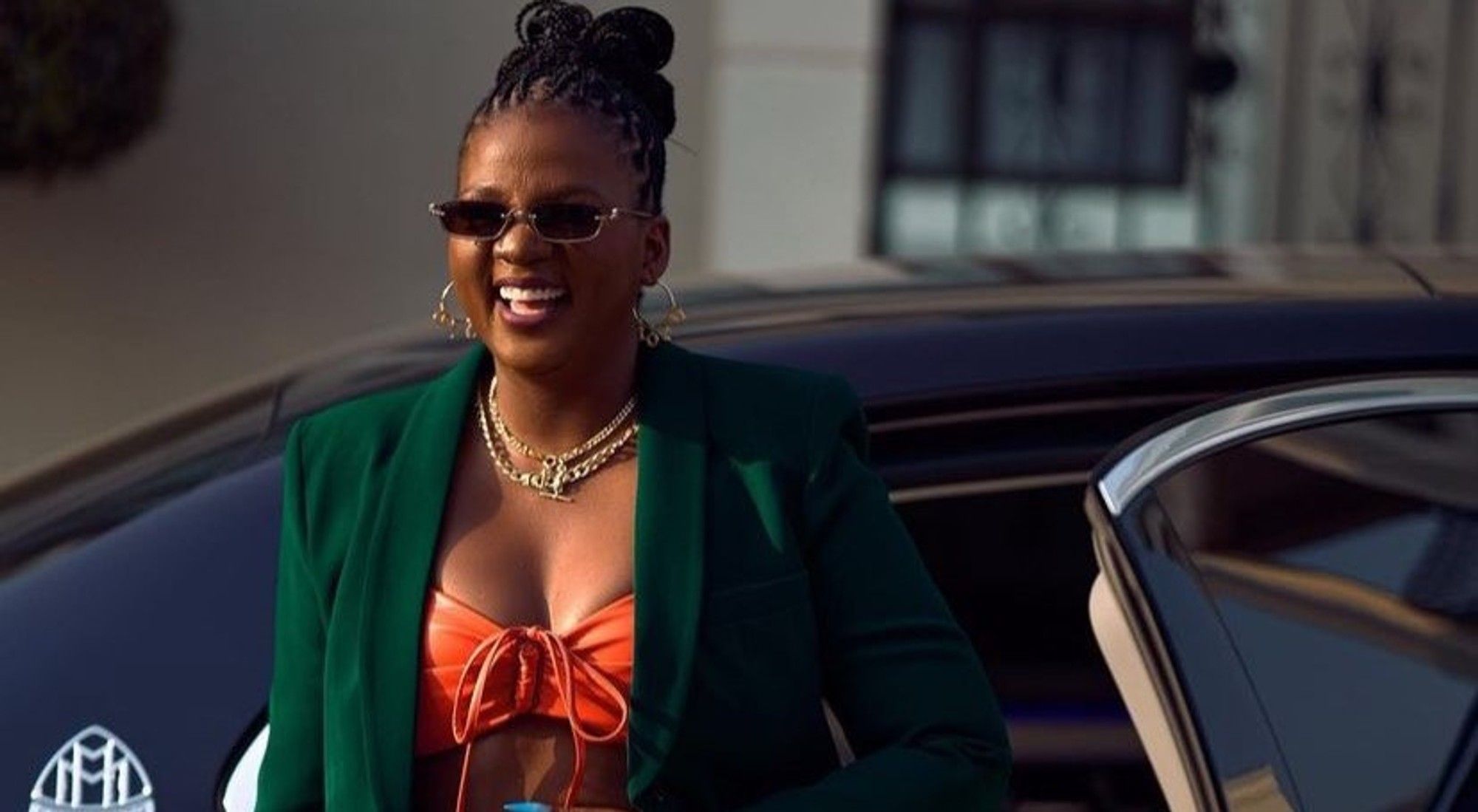 Fashionable woman smiling beside luxury car.