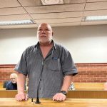 Man standing in courtroom during trial hearing.