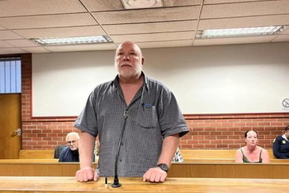 Man standing in courtroom during trial hearing.