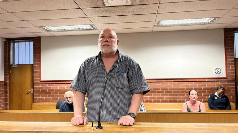 Man standing in courtroom during trial hearing.
