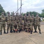 Soldiers in camouflage gear posing outdoors on base.