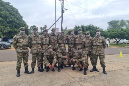 Soldiers in camouflage gear posing outdoors on base.
