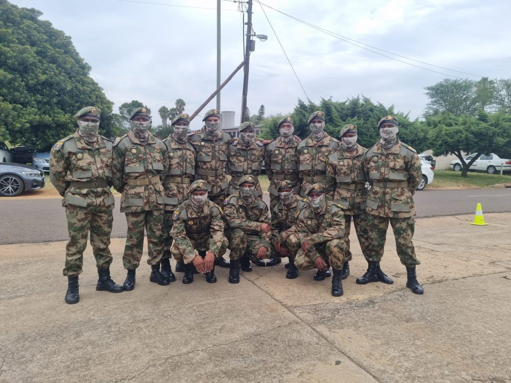 Soldiers in camouflage gear posing outdoors on base.