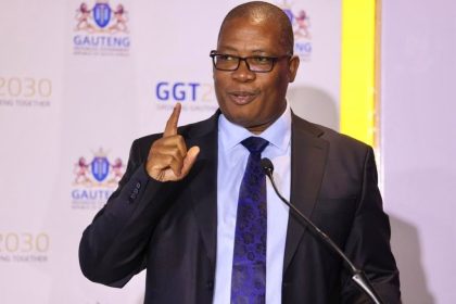 Man speaking at Gauteng event with microphone.
