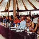 Conference attendees seated at long table.