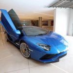 Blue sports car with open scissor doors in showroom.