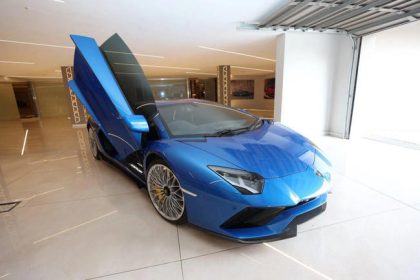 Blue sports car with open scissor doors in showroom.