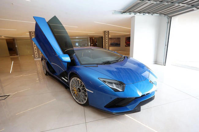Blue sports car with open scissor doors in showroom.
