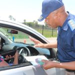 Traffic officer speaking to driver at a checkpoint.