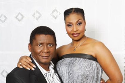 Smiling couple in elegant attire, white background.