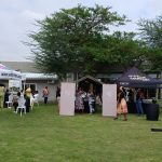 Outdoor event with tents and people gathering.